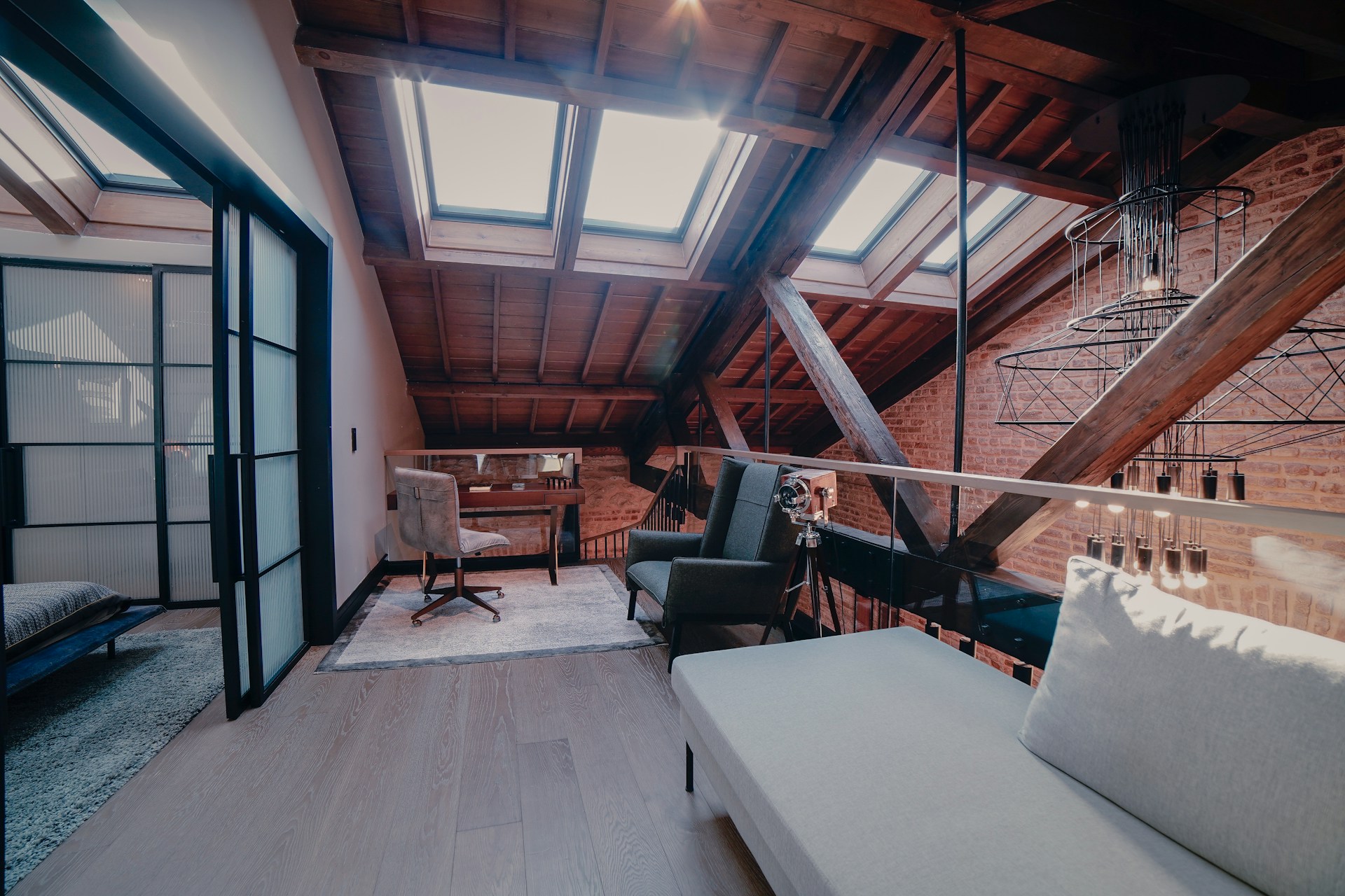 Close-up view of professionally converted loft space showing exposed wooden beams, dormer window, quality wooden flooring, and modern lighting demonstrating high-quality loft conversion workmanship