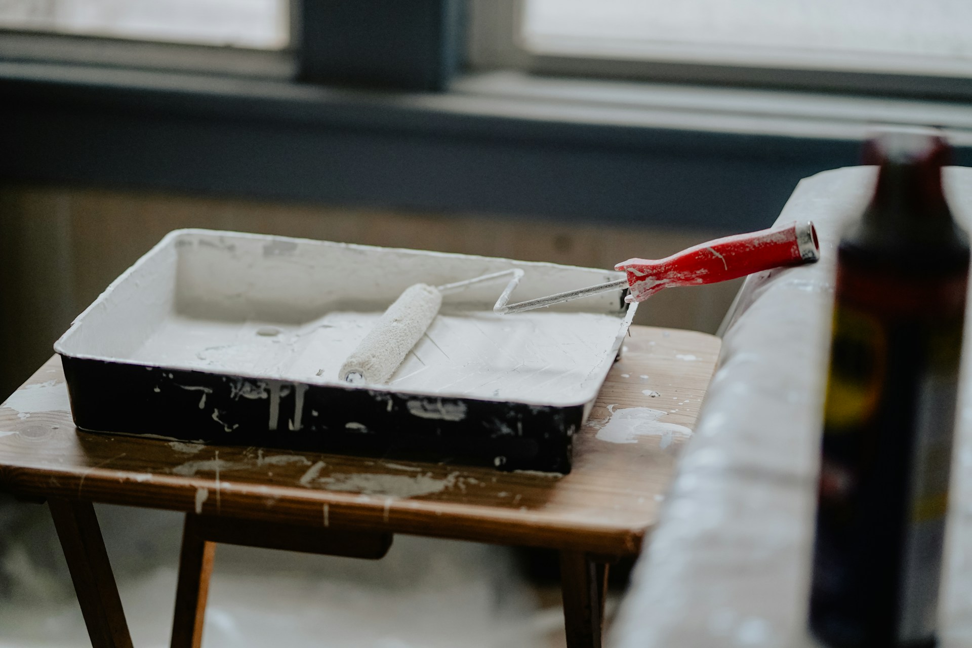 Paint roller and tray setup with brushes ready for interior house painting work