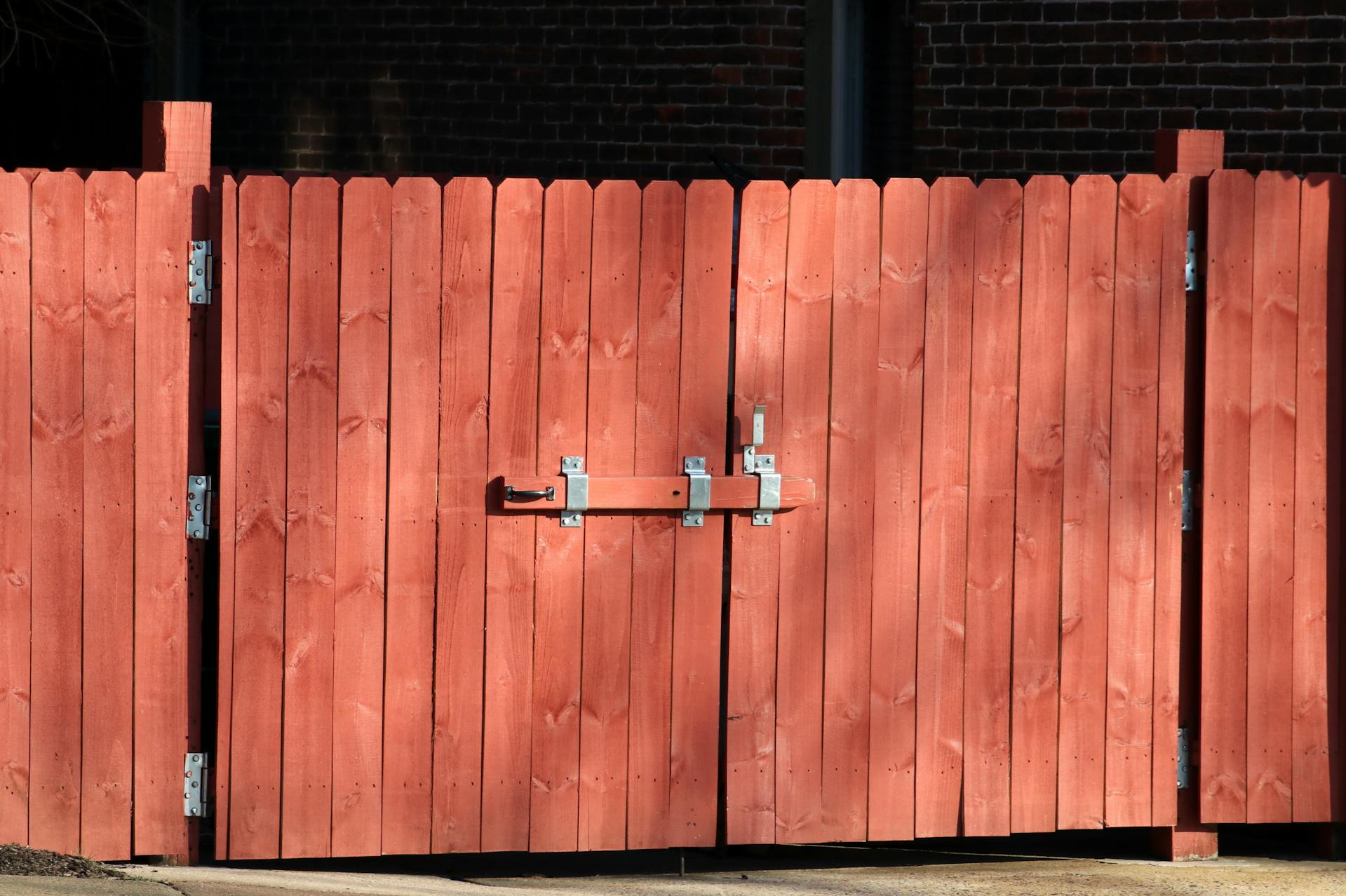 Beautiful wooden garden gate installed at property entrance with stone posts